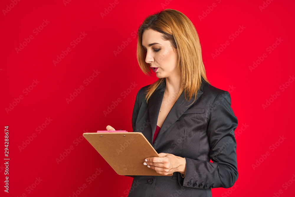 Young beautiful redhead businesswoman wearing suit writing on flip board Young beautiful redhead businesswoman wearing suit writing on flip board
