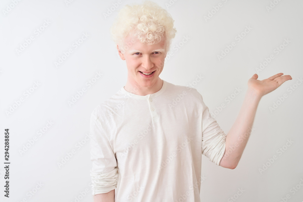 Young albino blond man wearing casual t-shirt standing over isolated white background smiling cheerful presenting and pointing with palm of hand looking at the camera. Young albino blond man wearing casual t-shirt standing over isolated white background smiling cheerful presenting and pointing with palm of hand looking at the camera.