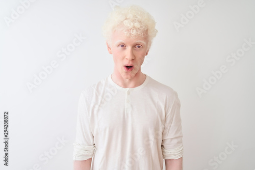 Young albino blond man wearing casual t-shirt standing over isolated white background afraid and shocked with surprise expression, fear and excited face.