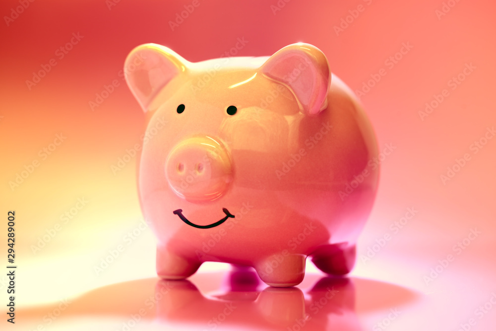 Smiling Piggybank on red and pink background. Saving money concept.