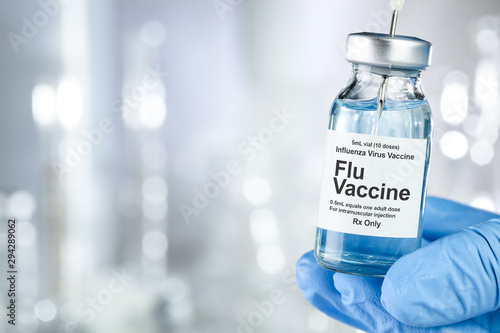 Healthcare concept with a hand in blue medical gloves holding Flu, Influenza, vaccine vial