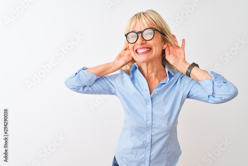 Foto Middle age businesswoman wearing elegant shirt and glasses over isolated white background Trying to hear both hands on ear gesture, curious for gossip