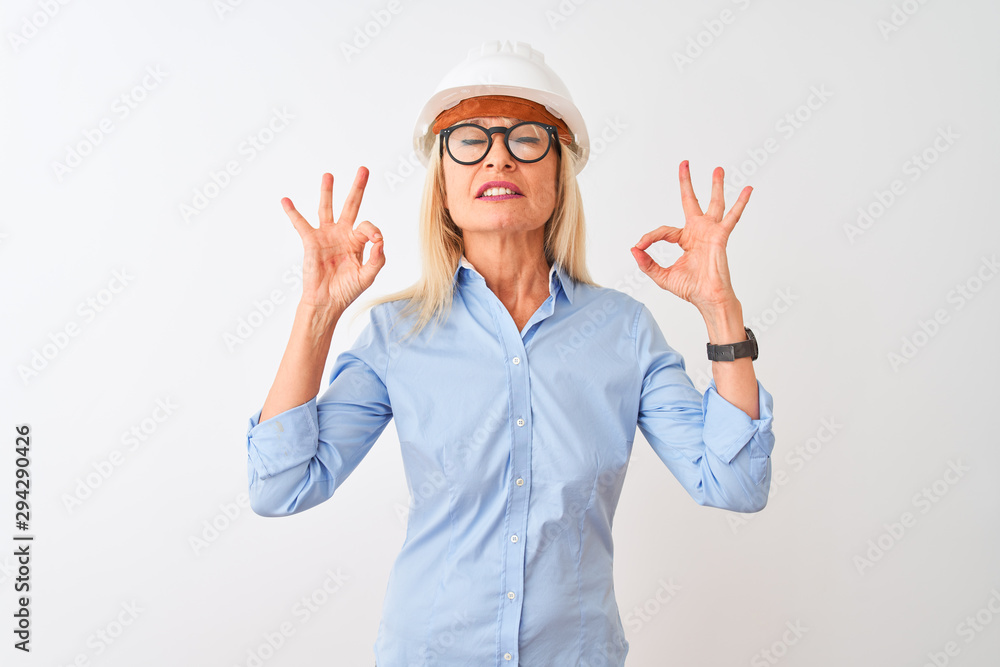 Middle age architect woman wearing glasses and helmet over isolated white background relax and smiling with eyes closed doing meditation gesture with fingers. Yoga concept. Middle age architect woman wearing glasses and helmet over isolated white background relax and smiling with eyes closed doing meditation gesture with fingers. Yoga concept.