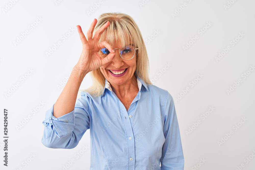 Obraz premium Middle age businesswoman wearing glasses and shirt standing over isolated white background with happy face smiling doing ok sign with hand on eye looking through fingers