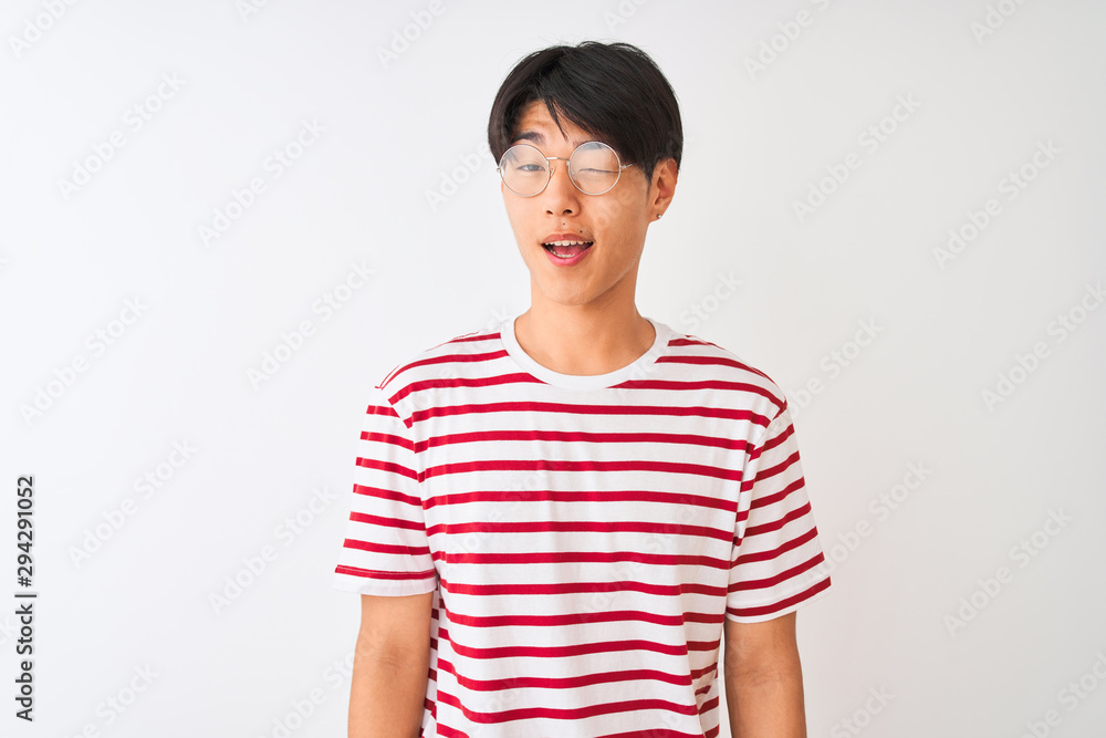 Young chinese man wearing glasses and striped t-shirt standing over isolated white background winking looking at the camera with sexy expression, cheerful and happy face. Young chinese man wearing glasses and striped t-shirt standing over isolated white background winking looking at the camera with sexy expression, cheerful and happy face.