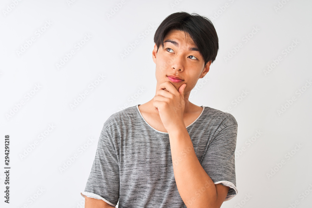 Young chinese man wearing casual t-shirt standing over isolated white background serious face thinking about question, very confused idea Young chinese man wearing casual t-shirt standing over isolated white background serious face thinking about question, very confused idea
