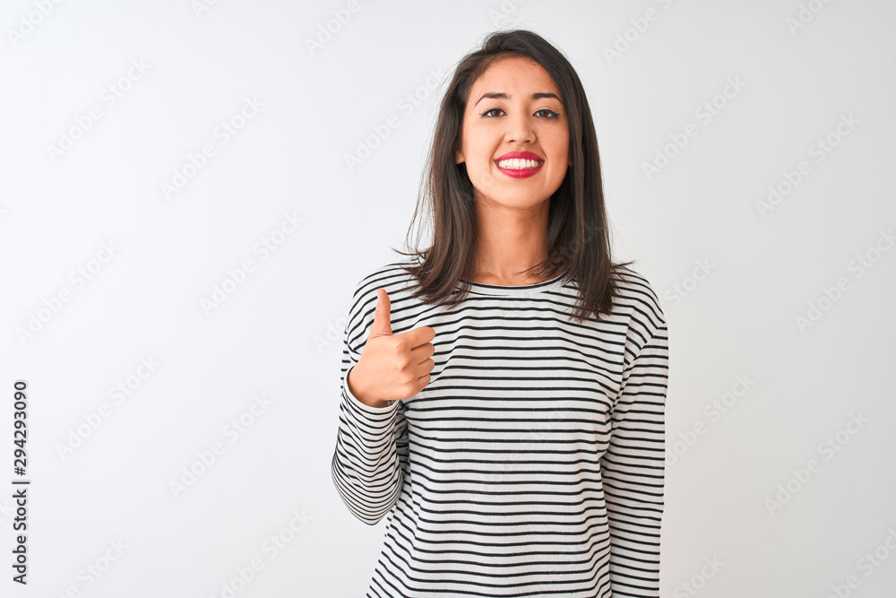Young beautiful chinese woman wearing striped t-shirt standing over isolated white background doing happy thumbs up gesture with hand. Approving expression looking at the camera showing success. Young beautiful chinese woman wearing striped t-shirt standing over isolated white background doing happy thumbs up gesture with hand. Approving expression looking at the camera showing success.