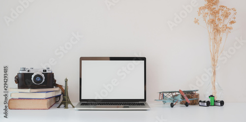 Minimal modern workplace with open blank screen laptop computer, camera and office supplies