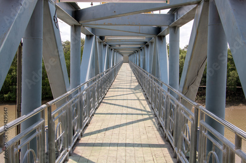 Fototapeta Naklejka Na Ścianę i Meble -  A empty metal foot bridge, perspective view. Construction of iron bridge over water. Pedestrian transition over the river.