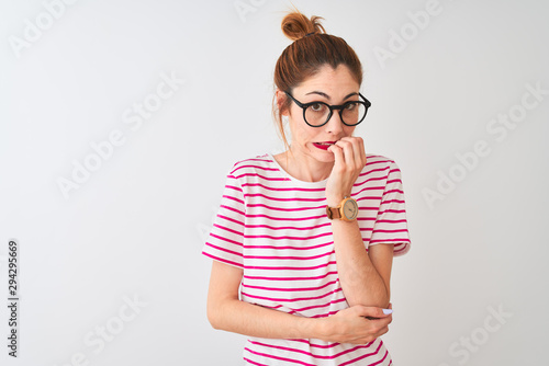 Redhead woman wearing glasses striped t-shirt and pigtail over isolated white background looking stressed and nervous with hands on mouth biting nails. Anxiety problem.