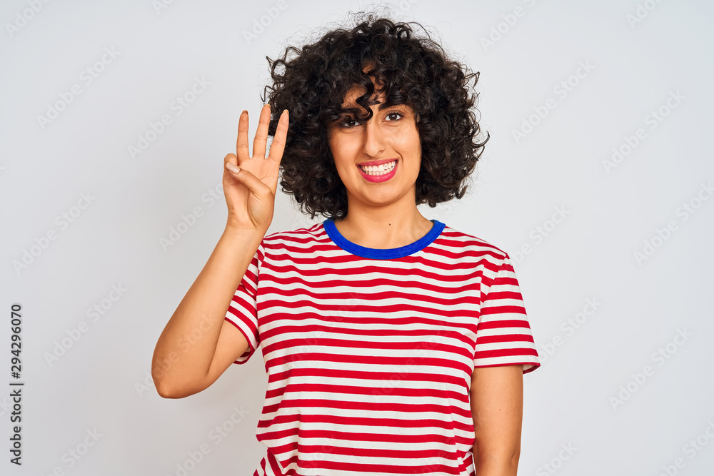 Young arab woman with curly hair wearing striped t-shirt over isolated white background showing and pointing up with fingers number three while smiling confident and happy. Young arab woman with curly hair wearing striped t-shirt over isolated white background showing and pointing up with fingers number three while smiling confident and happy.