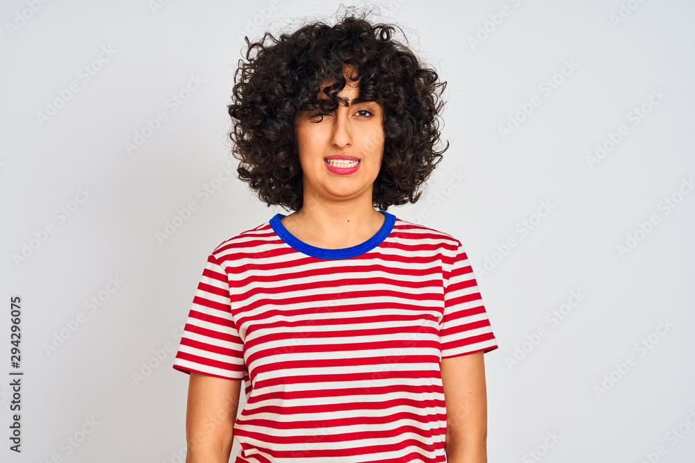 Young arab woman with curly hair wearing striped t-shirt over isolated white background winking looking at the camera with sexy expression, cheerful and happy face. Young arab woman with curly hair wearing striped t-shirt over isolated white background winking looking at the camera with sexy expression, cheerful and happy face.