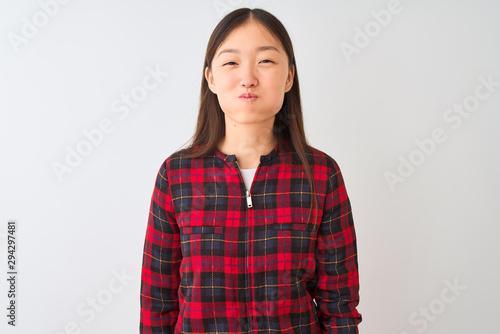 Young chinese woman wearing casual jacket standing over isolated white background puffing cheeks with funny face. Mouth inflated with air, crazy expression. © Krakenimages.com