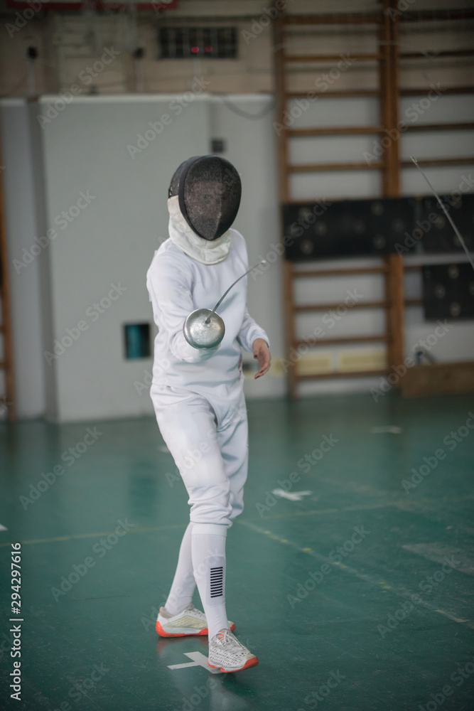 A young woman fencer standing in the fight pose holding a sword A young woman fencer standing in the fight pose holding a sword