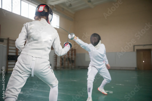 Two young women fencers having a training in full protection
