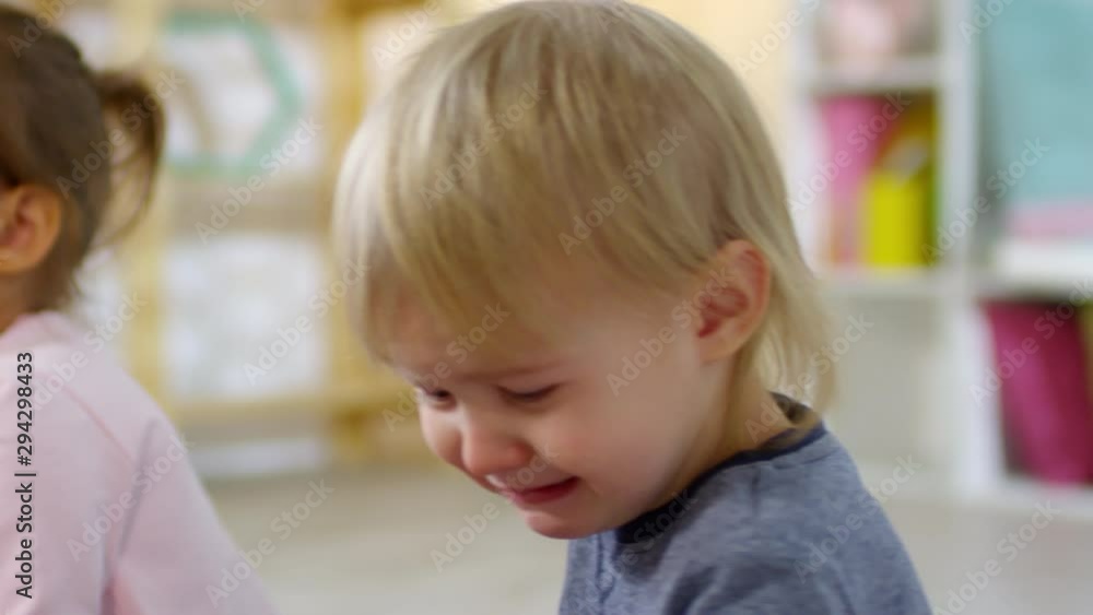 Close-up shot of upset 3 year old boy crying while playing with another kids in kindergarten Close-up shot of upset 3 year old boy crying while playing with another kids in kindergarten