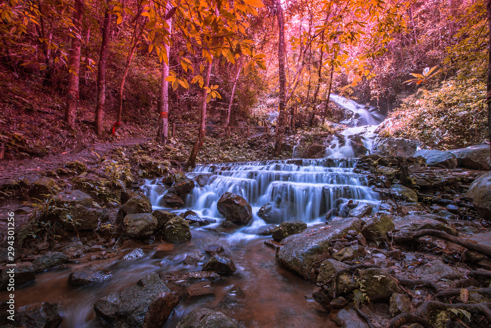 Natural blurred background of waterfalls, fast-flowing currents and water droplets from the wind blowing among the rocks and surrounded by big trees, spontaneous beauty Natural blurred background of waterfalls, fast-flowing currents and water droplets from the wind blowing among the rocks and surrounded by big trees, spontaneous beauty