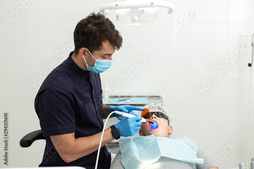 Dentist wearing blue gloves check-up teeths of little boy
