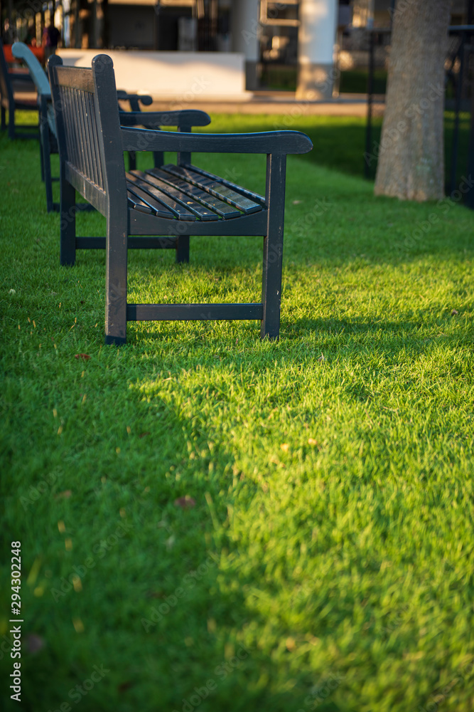 A cropping of blue wooden bench on fresh green grass in a small park with a nice sunlight casting. Feeling relax and peaceful. A cropping of blue wooden bench on fresh green grass in a small park with a nice sunlight casting. Feeling relax and peaceful.
