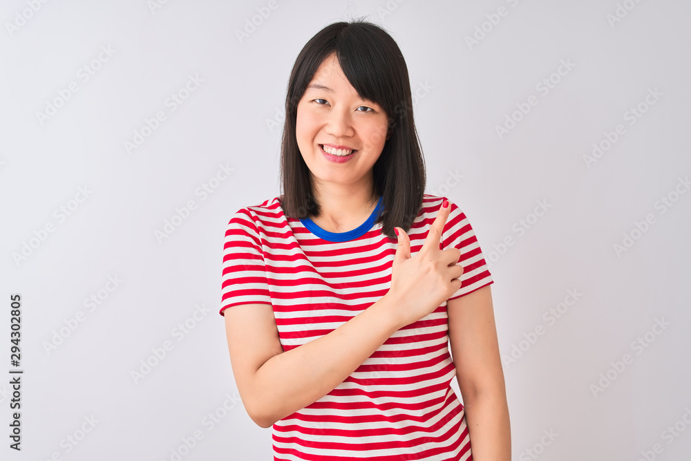 Young beautiful chinese woman wearing red striped t-shirt over isolated white background cheerful with a smile on face pointing with hand and finger up to the side with happy and natural expression Young beautiful chinese woman wearing red striped t-shirt over isolated white background cheerful with a smile on face pointing with hand and finger up to the side with happy and natural expression