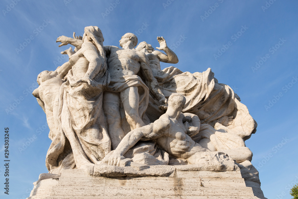 Marble composition on the bridge of Victor Emmanuel II over the Tiber River in Rome, symbolizing freedom and unity.