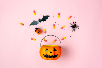 Table top view aerial image of decorations Happy Halloween day background holiday concept.Flat lay objects to party Jack O lantern pumpkins bucket and spider with candy sweet on pink  paper.