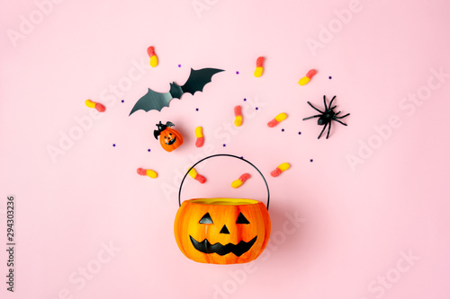 Table top view aerial image of decorations Happy Halloween day background holiday concept.Flat lay objects to party Jack O lantern pumpkins bucket and spider with candy sweet on pink  paper.