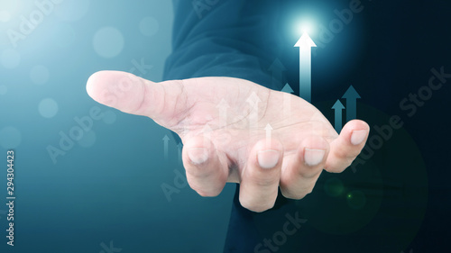 Tablou pe pânză Close up Asian Man standing and shows outstretched hand with Arrow Visual Graphic open palm on Light of Len flare and Boke blue background