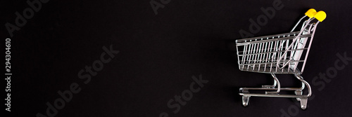 Shopaholic. Buyer. Shopping concept. Close-up. From above. Isolated shopping trolley on a black background. Copy space. Banner.