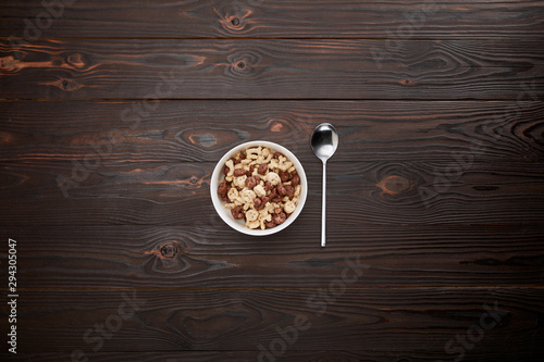 Top view of spoon near cereal in bowl on wooden surface