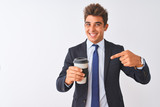Young handsome businessman wearing suit holding coffee over isolated white background very happy pointing with hand and finger