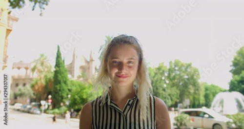 Young Blonde Pretty Woman in a Smart Stripe Shirt standing in the Lovely Spanish Palma City in Front of a Water Fountian. Gap Year Girl Student in Europe.Smiling Enjoying the sun Smiling photo