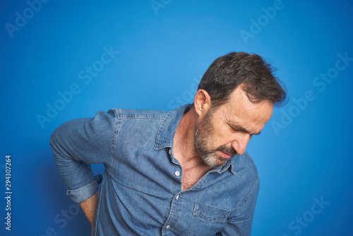 Handsome middle age senior man with grey hair over isolated blue background Suffering of backache, touching back with hand, muscular pain