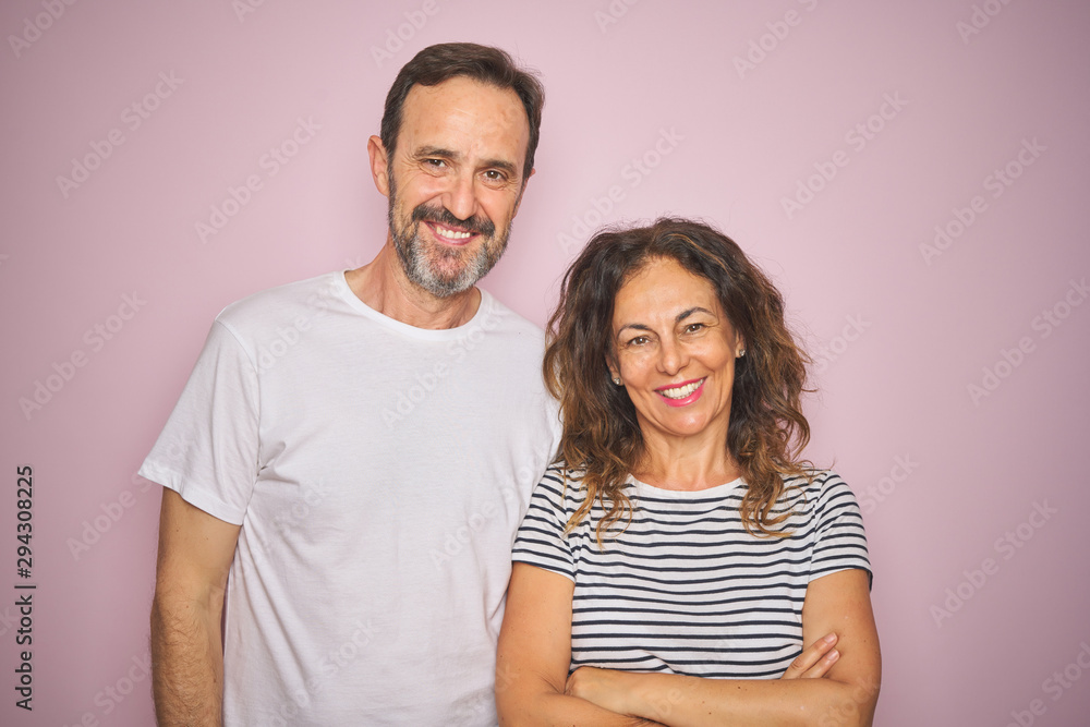 Fototapeta premium Beautiful middle age couple together standing over isolated pink background happy face smiling with crossed arms looking at the camera. Positive person.