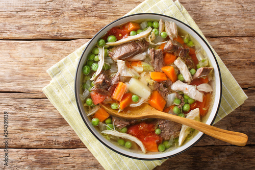 Thick slowly cooked soup with vegetables and meat close-up in a plate. Horizontal top view