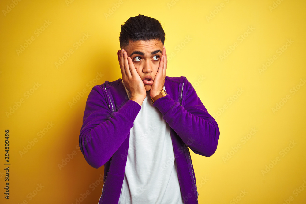 Young brazilian man wearing purple sweatshirt standing over isolated yellow background Tired hands covering face, depression and sadness, upset and irritated for problem Young brazilian man wearing purple sweatshirt standing over isolated yellow background Tired hands covering face, depression and sadness, upset and irritated for problem