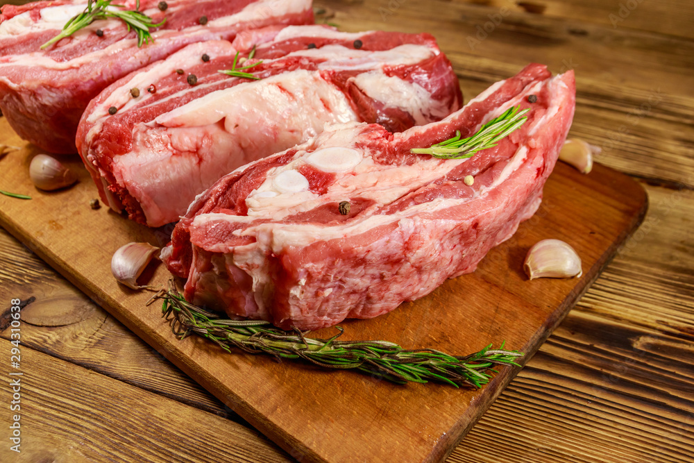 Raw pork ribs with spices, garlic and rosemary on wooden table Raw pork ribs with spices, garlic and rosemary on wooden table