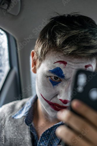Male cosplayer making selfie with his smartphone in the backseat of the car close up portrait 