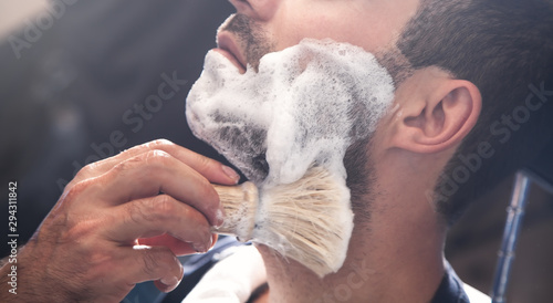 Obraz na plátně Hairdresser applying cream for shaving.
