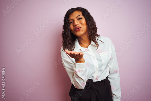 Transsexual transgender businesswoman standing over isolated pink background looking at the camera blowing a kiss with hand on air being lovely and sexy. Love expression.