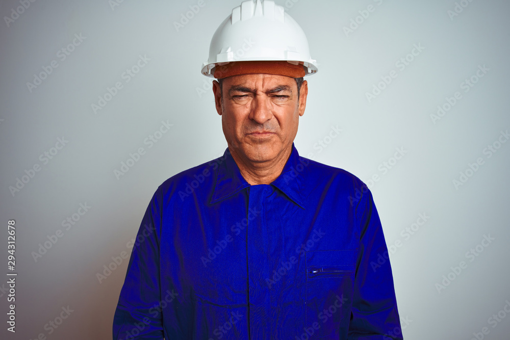 Handsome middle age worker man wearing uniform and helmet over isolated white background depressed and worry for distress, crying angry and afraid. Sad expression.