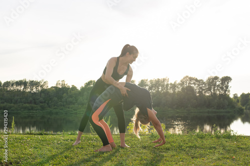 Healthy lifestyle and people concept - Flexible women doing yoga in the summer park