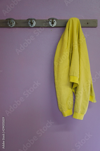 une veste jaune accrochée à un porte-manteau sur un mur violet photo