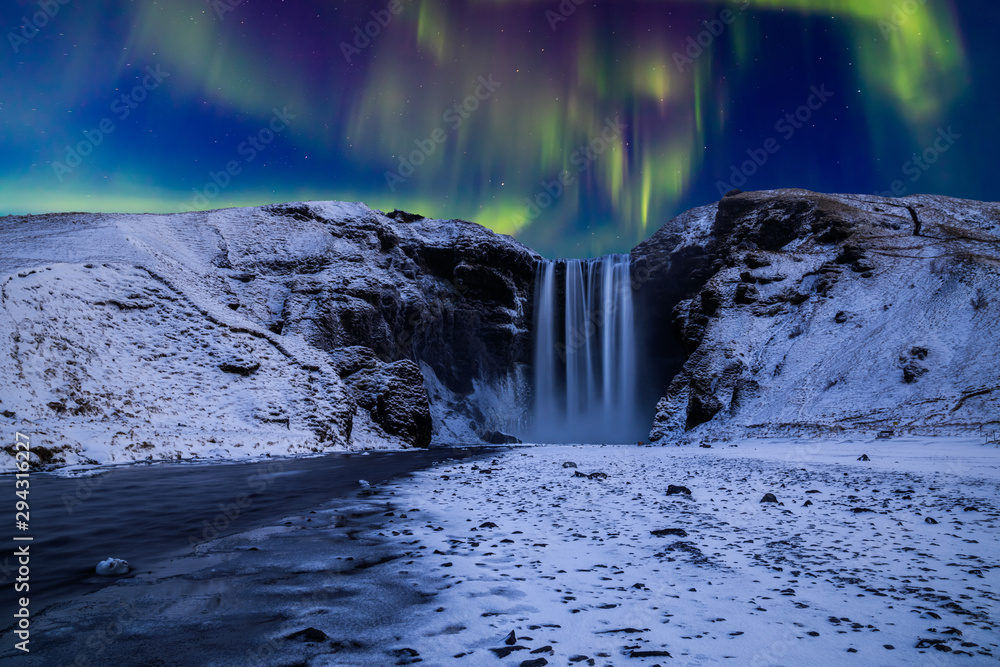 Skogafoss waterfall in the winter at night under the northern lights. Iceland. - obrazy, fototapety, plakaty 