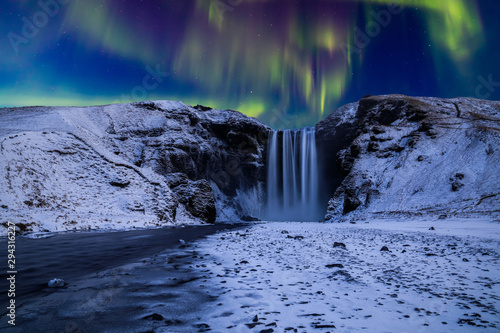 Skogafoss waterfall in the winter at night under the northern lights. Iceland.
