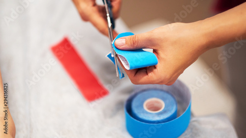 oman massage therapist prepares kinesio tape cuts with scissors photo