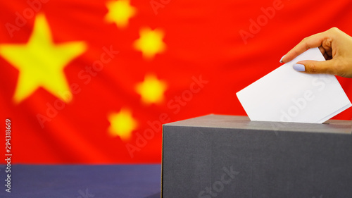 Hand holding ballot paper for election vote concept. elections, The hand of woman putting her vote in the ballot box. China Flag on background.