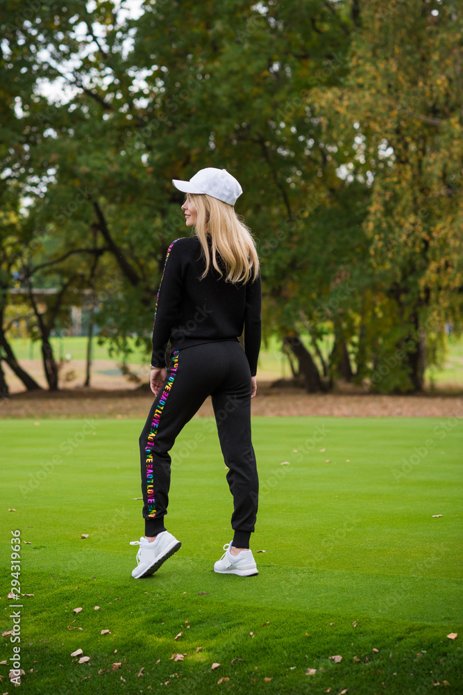 Young woman in tracksuit , on a green city park  sports or fit lifestyle 