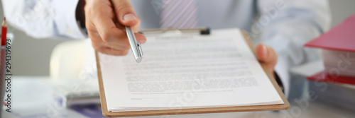 Male arm in suit offer contract form on clipboard pad and silver pen to sign closeup. Strike a bargain for profit white collar motivation union decision corporate sale insurance agent concept photo
