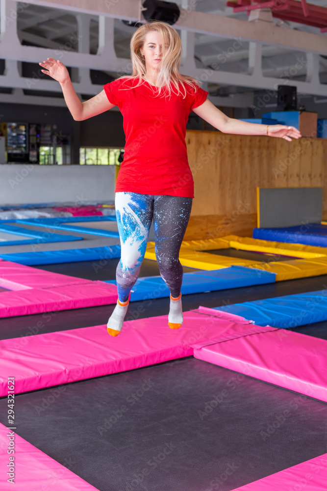 Fitness, fun, leisure and sport activity concept - Young happy woman jumping  on a trampoline indoors Stock Photo | Adobe Stock